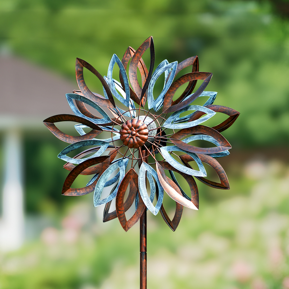 Decorative metal windmill in a garden setting with blurred background